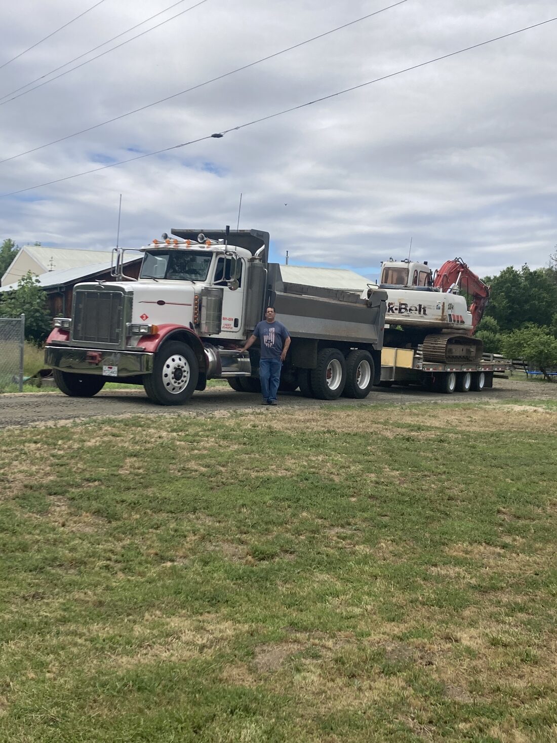 Russco Enterprises owner standing beside the company's semi dump truck and excavator in Douglas County, Oregon.