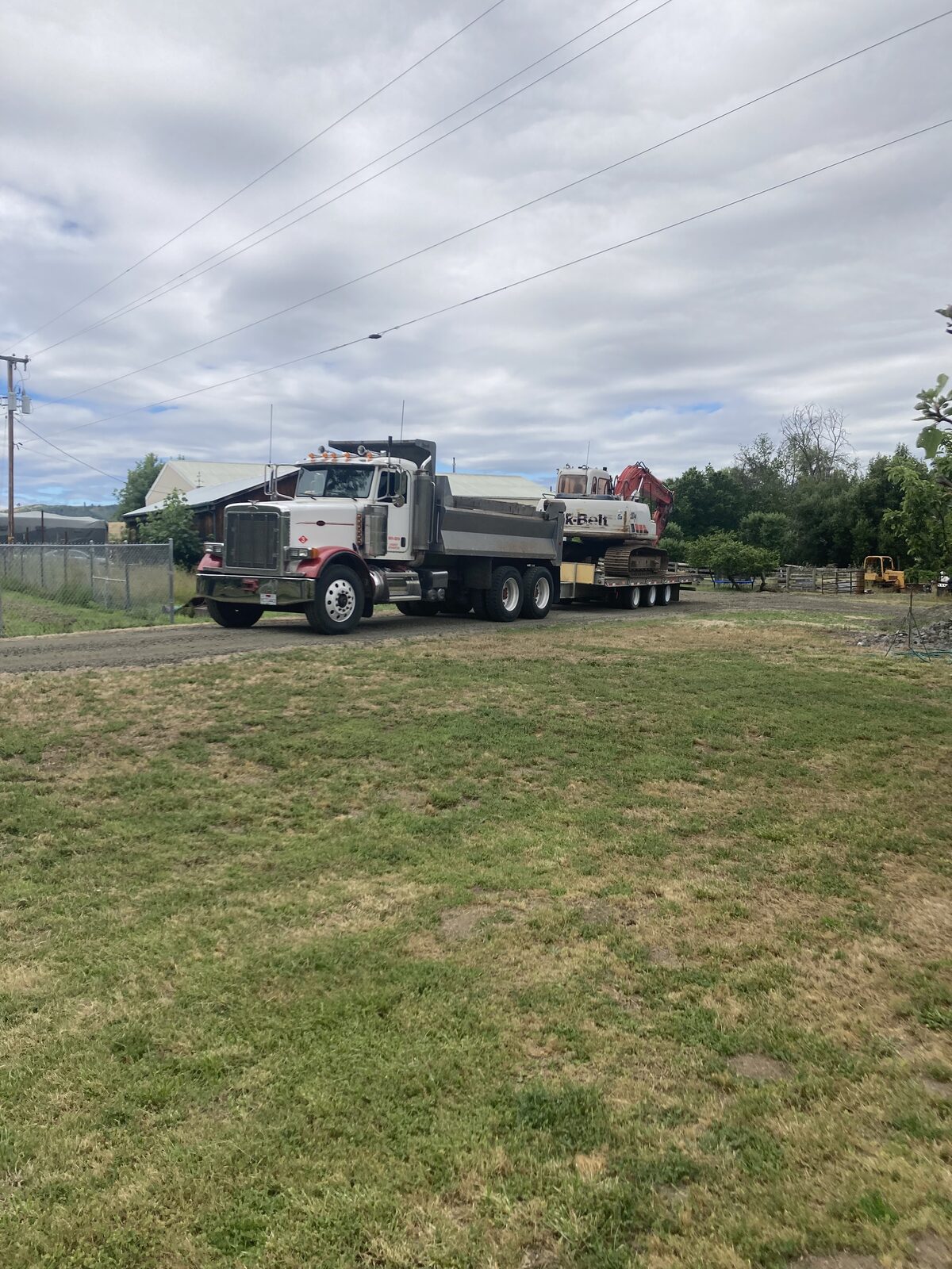 Russco's full-size excavator loaded on a trailer behind the semi dump truck, ready to move to a job site in Douglas County.